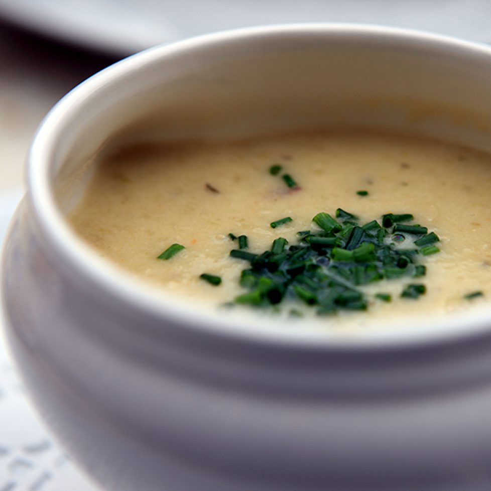 White bowl of chicken & vegetable soup with a sprinkling of chives